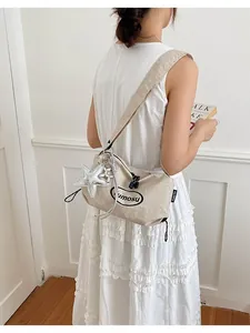 Back view of model wearing a beige nylon shoulder bag with a silver star charm