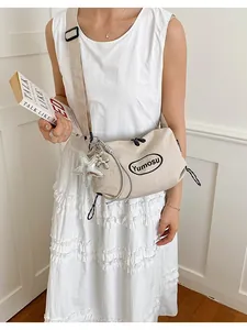 Stylish beige lightweight crossbody bag with rope strap shown worn by model in white dress