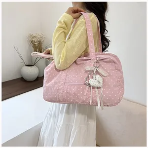 Side view of a pink polka dot Boston bag carried by a model in a minimalist room
