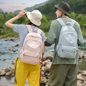 Couple wearing stylish lightweight pink and light blue backpacks in outdoor nature