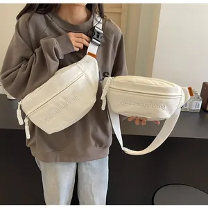 Detail of white canvas crossbody fanny packs with embroidered studio logo design