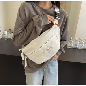 Detailed close-up view of a white sporty crossbody chest bag worn by a model in a studio