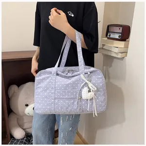 Lavender polka dot travel tote bag held by a model in a casual lifestyle setting