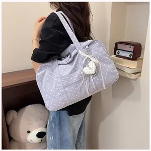 Close-up of a purple polka dot travel tote bag with heart charm on shoulder