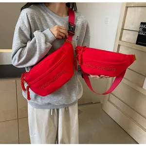 Detail view of vibrant red cross-body chest bags with embroidered studio bag logo.