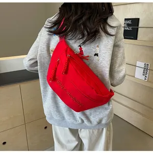 Rear view of a stylish red athletic sling bag worn over a grey sweatshirt in a room