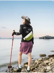 Frau mit einer grün-weißen wasserdichten Sport-Brusttasche bei einer Outdoor-Wanderung