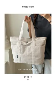 Detailansicht eines Modells, das eine große beige Canvas-Tragetasche für die Arbeit trägt