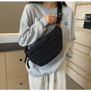 Detailed shot of a black sporty crossbody chest bag worn with a grey sweatshirt.