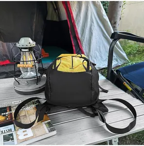 Mochila de exterior impermeable amarilla y negra sobre mesa de camping en una tienda
