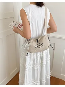 Model wearing a minimalist beige nylon crossbody bag with a star keychain charm.