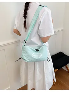 Detailed view of a lightweight mint green nylon crossbody bag worn by a female model.