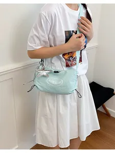 Model wearing a stylish mint green lightweight crossbody bag with star charm detail