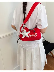 Lifestyle shot of a red lightweight crossbody bag featuring a silver star charm accessory.