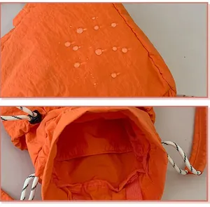 Detailansicht des wasserdichten Nylons und des Innenraums des orangen Kordelzug-Rucksacks