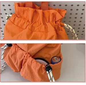 Detailansicht des orangefarbenen Nylon-Rucksacks mit Kordelzug und Seitentasche.