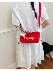 Model wearing a vibrant red lightweight nylon crossbody bag with a silver star charm