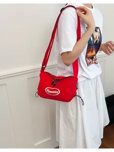 Vibrant red lightweight crossbody bag worn by model against a white paneled interior wall