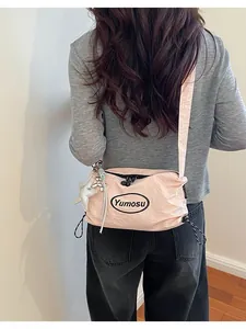 Back view of a model wearing a pink lightweight nylon crossbody bag with star charm detail.