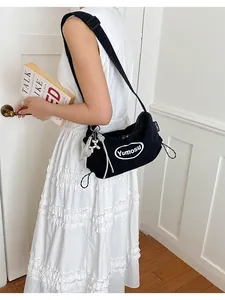 Minimalist black canvas shoulder bag with unique drawstring detail and white logo print