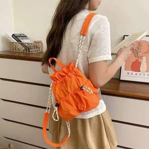 Detailansicht eines leuchtend orangefarbenen Nylon-Kordelzug-Rucksacks an einem Model.