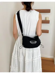 Back view of a lightweight black crossbody bag with drawstring details on a white dress