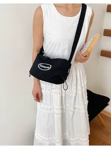 Minimalist black lightweight nylon crossbody bag shown in a lifestyle model shot