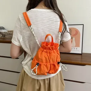 Detailansicht eines leuchtend orangefarbenen, wasserdichten Nylon-Rucksacks am Modell.