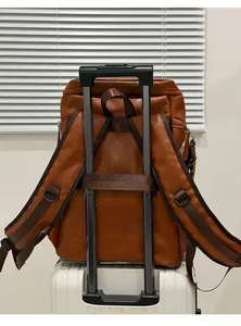 Detail of vintage brown leather backpack mounted on a white luggage trolley handle