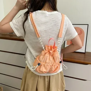 Rückansicht einer Frau mit einem orangefarbenen Nylon-Rucksack mit Kordelzug im Innenbereich
