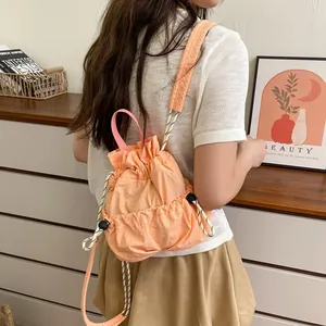 Detailansicht eines pfirsichfarbenen Nylon-Rucksacks mit Kordelzug, getragen von Model
