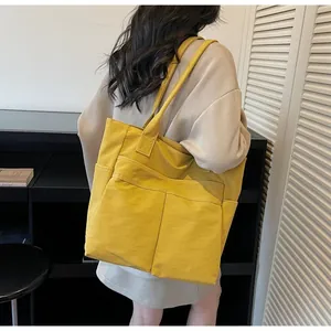 Donna che indossa una grande borsa tote in tela gialla sulla spalla, vista lifestyle
