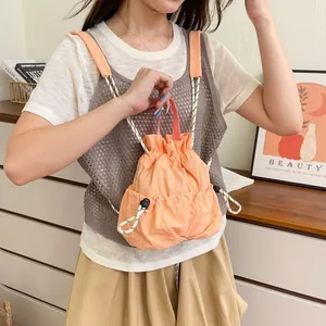 Detail des wasserdichten orangefarbenen Nylon-Rucksacks mit Kordelzug am Modell.