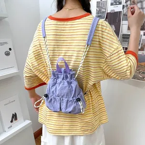 Rückansicht einer Frau mit einem lila Nylon-Rucksack mit Kordelzug in Freizeitoptik