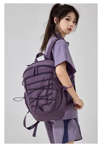Side view of a purple outdoor backpack with bungee cord design on a female model