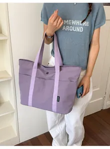 Detailansicht einer lila großen Tragetasche, getragen von einem Modell in Innenräumen