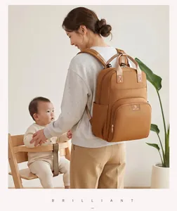 Madre asiática con bolso cambiador multifuncional marrón en un hogar luminoso.