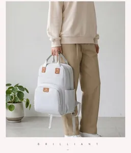 Bolso cambiador gris minimalista de gran capacidad sostenido por una modelo.
