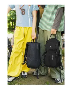 Dos mochilas negras de senderismo sostenidas por modelos en un entorno de acampada soleado.