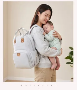 Madre asiática con la elegante mochila cambiador gris de gran capacidad cargando a su bebé