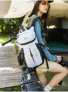 Mochila ligera de ciclismo con rejilla blanca usada por una modelo en un camping al aire libre.