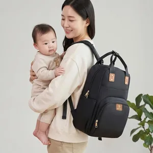 Mochila pañalera negra multifuncional de gran capacidad llevada por una madre con su bebé