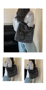 A detailed view of a large capacity black denim tote bag featuring multiple pockets