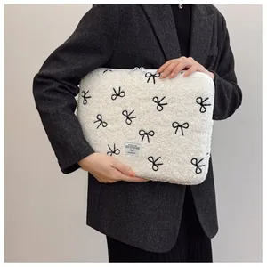 Witte pluche laptoptas met geborduurde zwarte strikjes vastgehouden door model