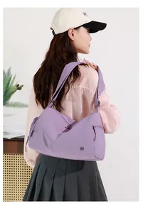 Back view of a functional purple sports gym bag carried by a model in a casual outfit