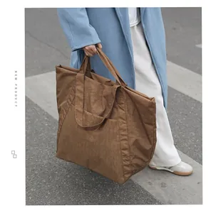 Lifestyle-Detail einer großen braunen, plissierten Nylon-Einkaufstasche für Damen im Freien