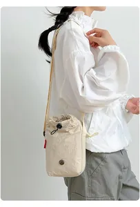 Bolso bandolera multifuncional beige con cordón para móvil y botella en una modelo
