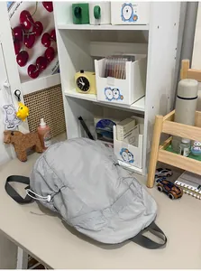 Lightweight grey nylon drawstring backpack for school and commuting on a lifestyle desk