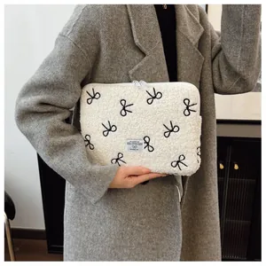 Detailweergave van de zachte witte pluche laptoptas met geborduurde zwarte strikjes