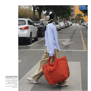 Große orangefarbene Nylon-Einkaufstasche mit Knitteroptik in einer städtischen Straße